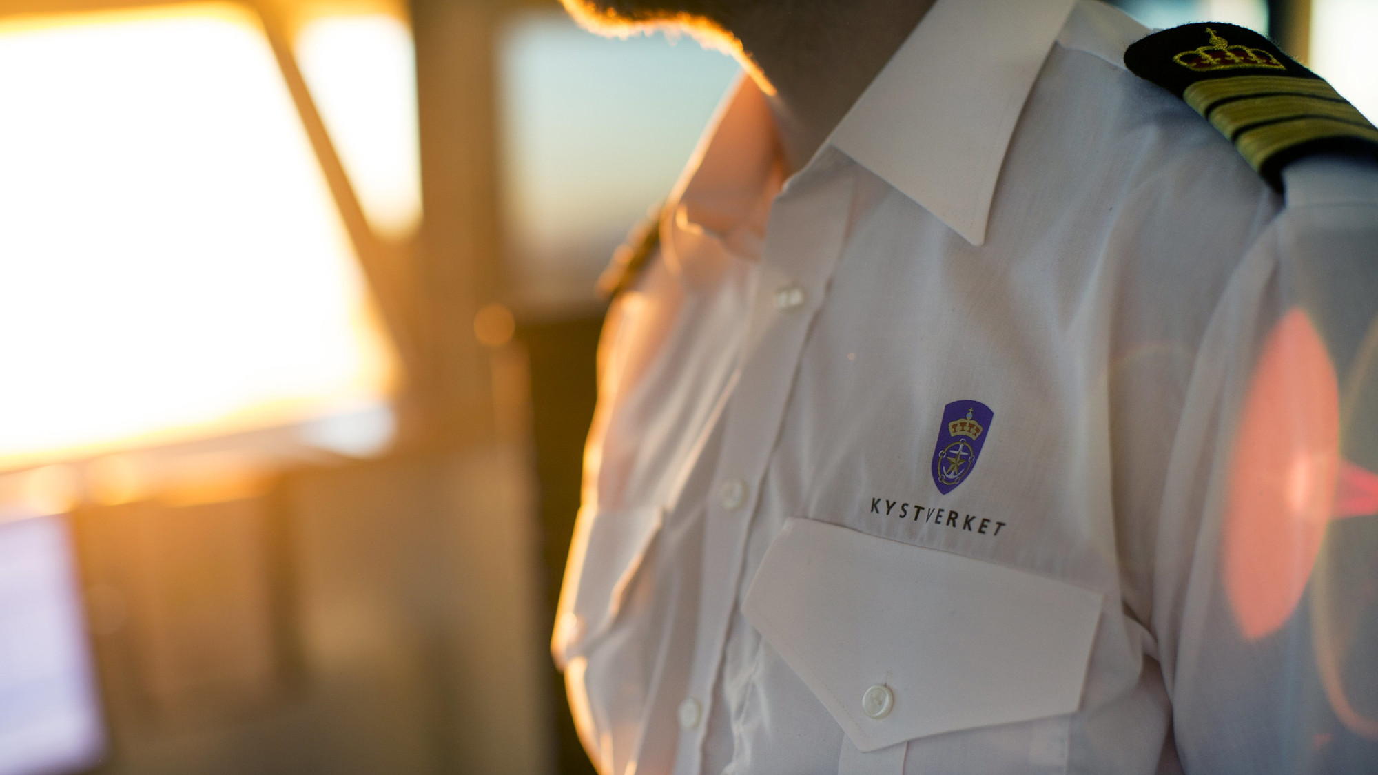 Nærbilde av uniformen til en maritim trafikkleder med distinksjoner og logo