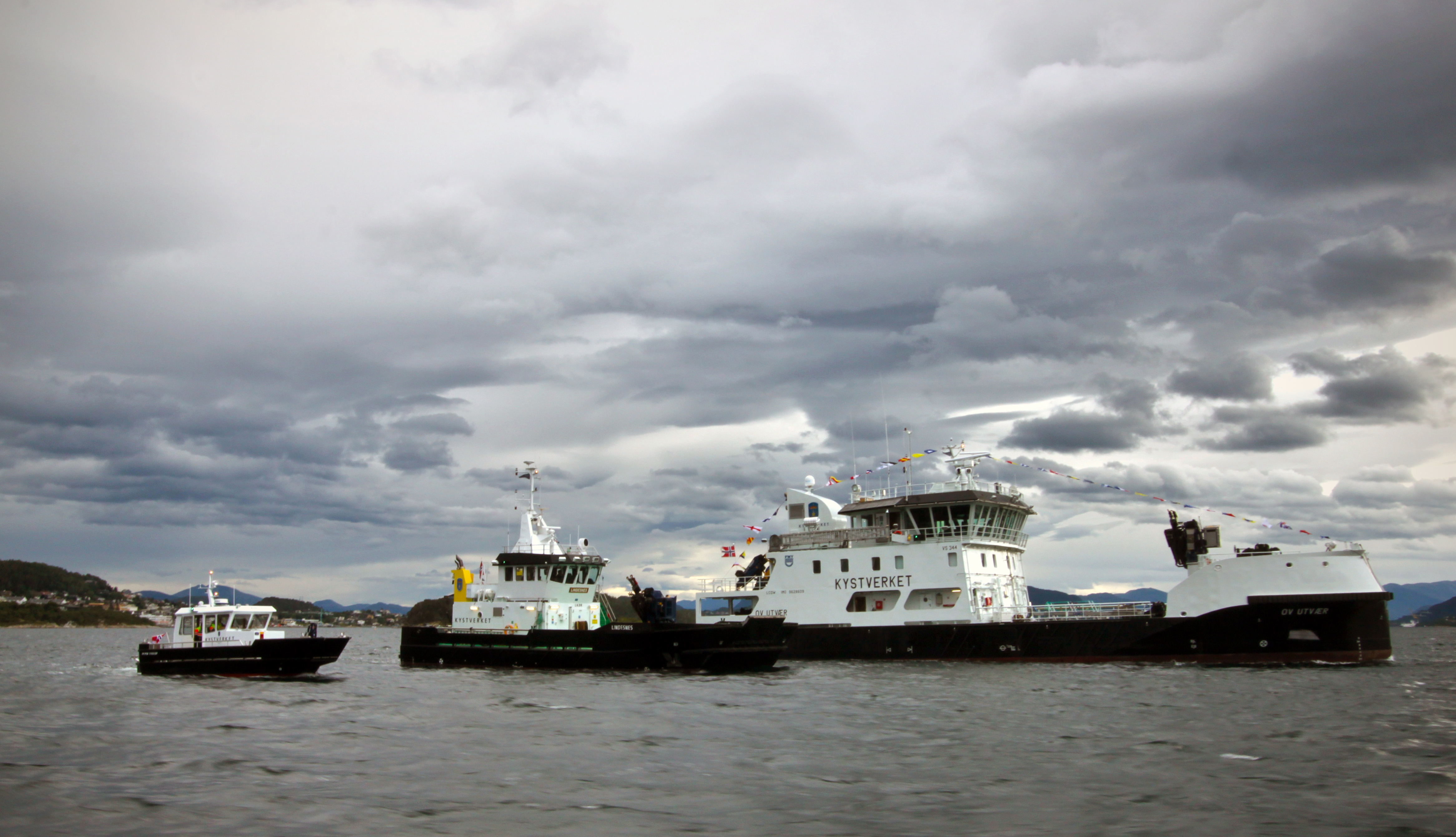 Tre fartøy ligg side om side.